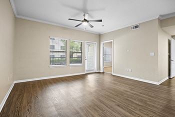 An empty living room with a ceiling fan and a window